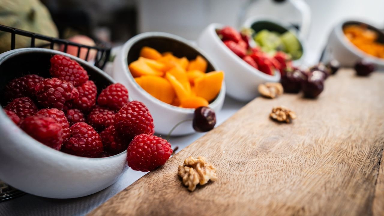 Bols de framboises et d'abricots sur une planche en bois, photo culinaire pour Le Petit Luce